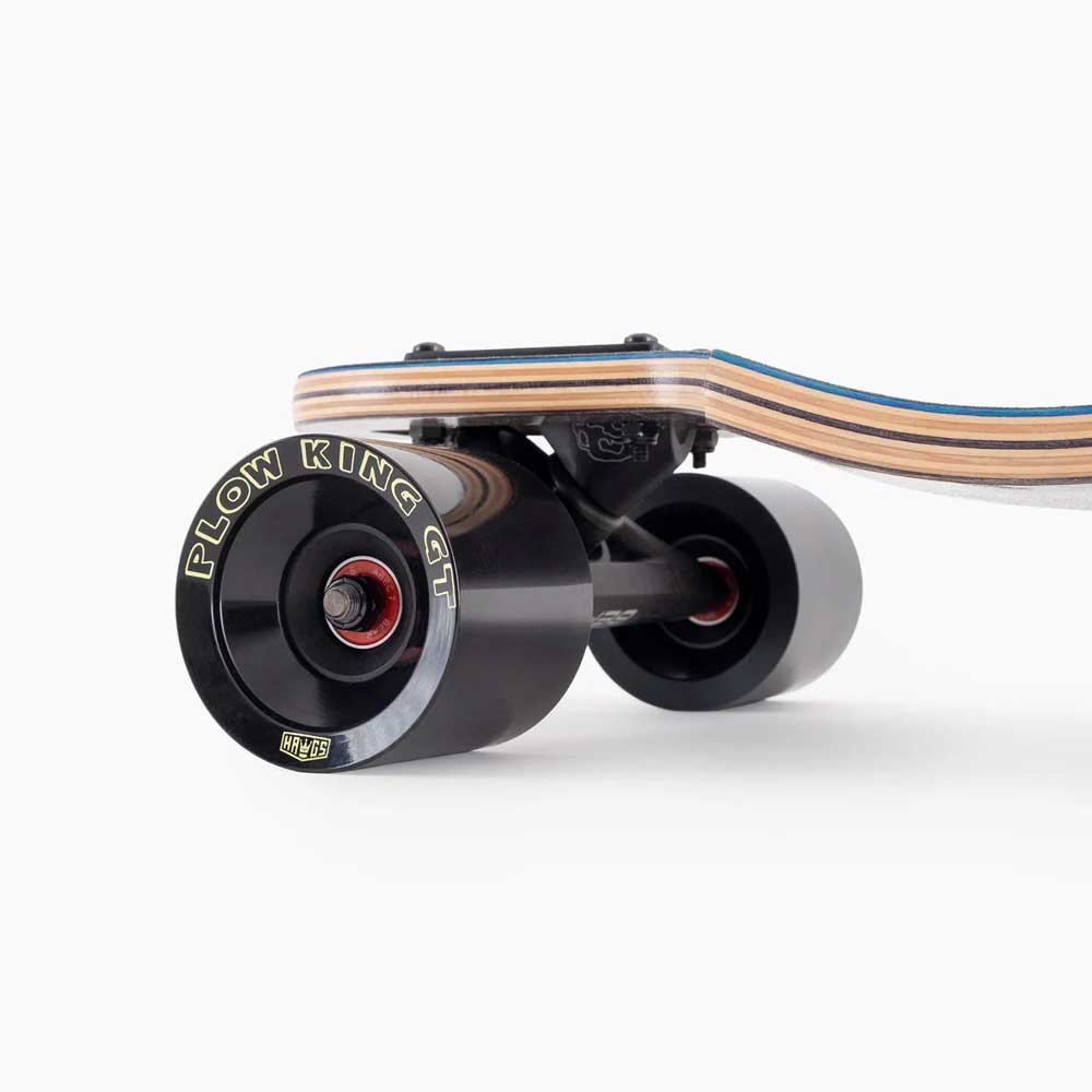 Close-up of the Atmosphere Switchblade 40 Landyachtz Complete Skateboard’s rear, showing black “PLOW KING GT” wheels and a multi-layered wooden deck with black and blue accents.