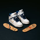 A pair of Ivory Sand Blue Void Dunk High Pro x Beyond IU4491100 Nike SB skateboarding shoes are displayed with navy laces beside insoles that showcase cartoon-style artwork, all set against a black background.