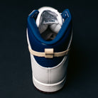 A single Ivory Sand Blue Void Dunk High Pro x Beyond IU4491100 Nike SB Skateboarding Shoe is viewed from the back, featuring a beige strap and the word "BEYOND" visible inside near the heel. The shoe rests on a dark surface with a dark background.