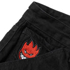 Close-up of the Bighead Fill Denim Pant Black by Spitfire Wheels, showing a black denim pocket with an embroidered red Spitfire flame face featuring white eyes and a mischievous grin peeking out from the pocket.