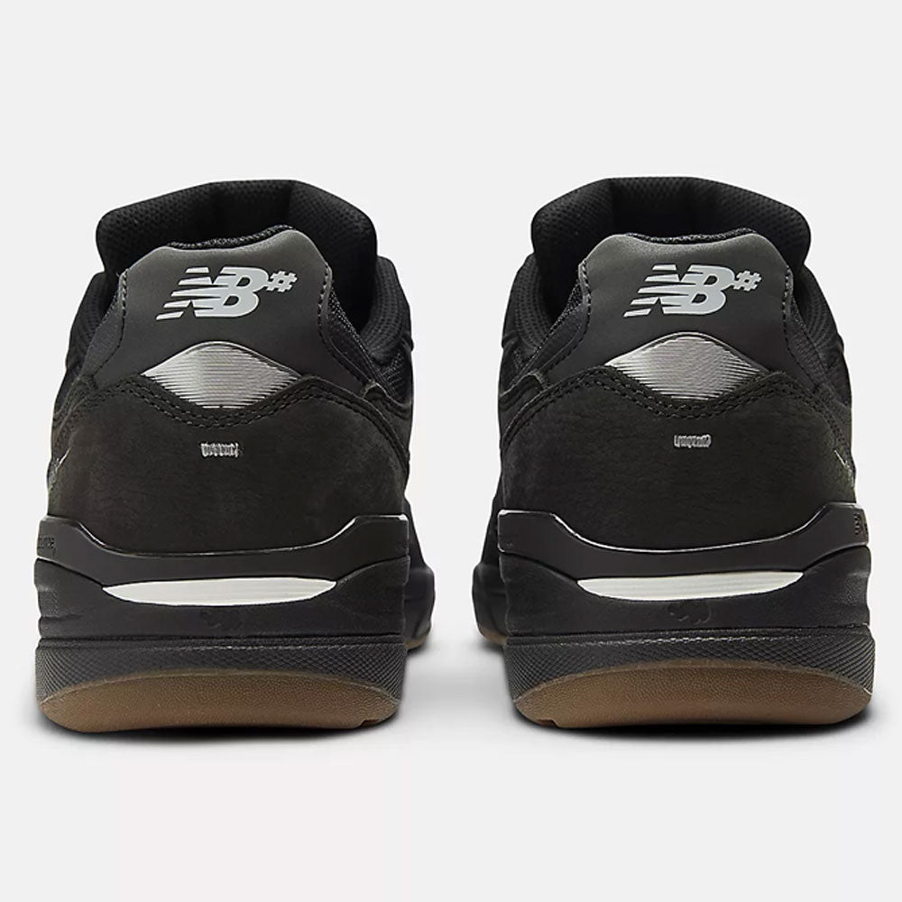 A pair of Black 933 NAP New Balance Numeric suede skateboarding shoes viewed from the back, showing silver NB heel logos, black midsoles with silver accents, and gum outsoles.