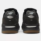 A pair of Black 933 NAP New Balance Numeric suede skateboarding shoes viewed from the back, showing silver NB heel logos, black midsoles with silver accents, and gum outsoles.