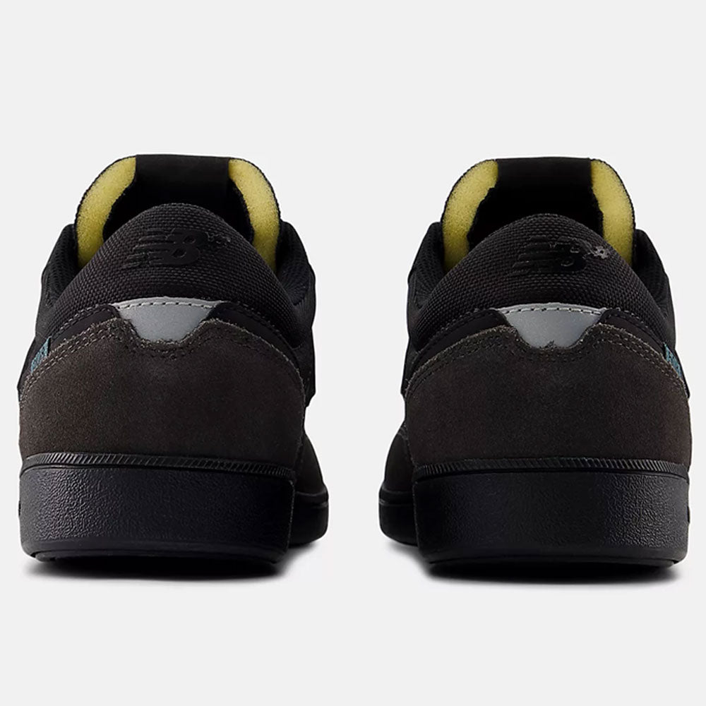 Rear view of Black Cement New Spruce 508 TAC New Balance Numeric suede skateboarding shoes, with mesh details, yellow inner lining, and reflective heel accents, shown against a light gray background.