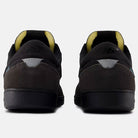 Rear view of Black Cement New Spruce 508 TAC New Balance Numeric suede skateboarding shoes, with mesh details, yellow inner lining, and reflective heel accents, shown against a light gray background.