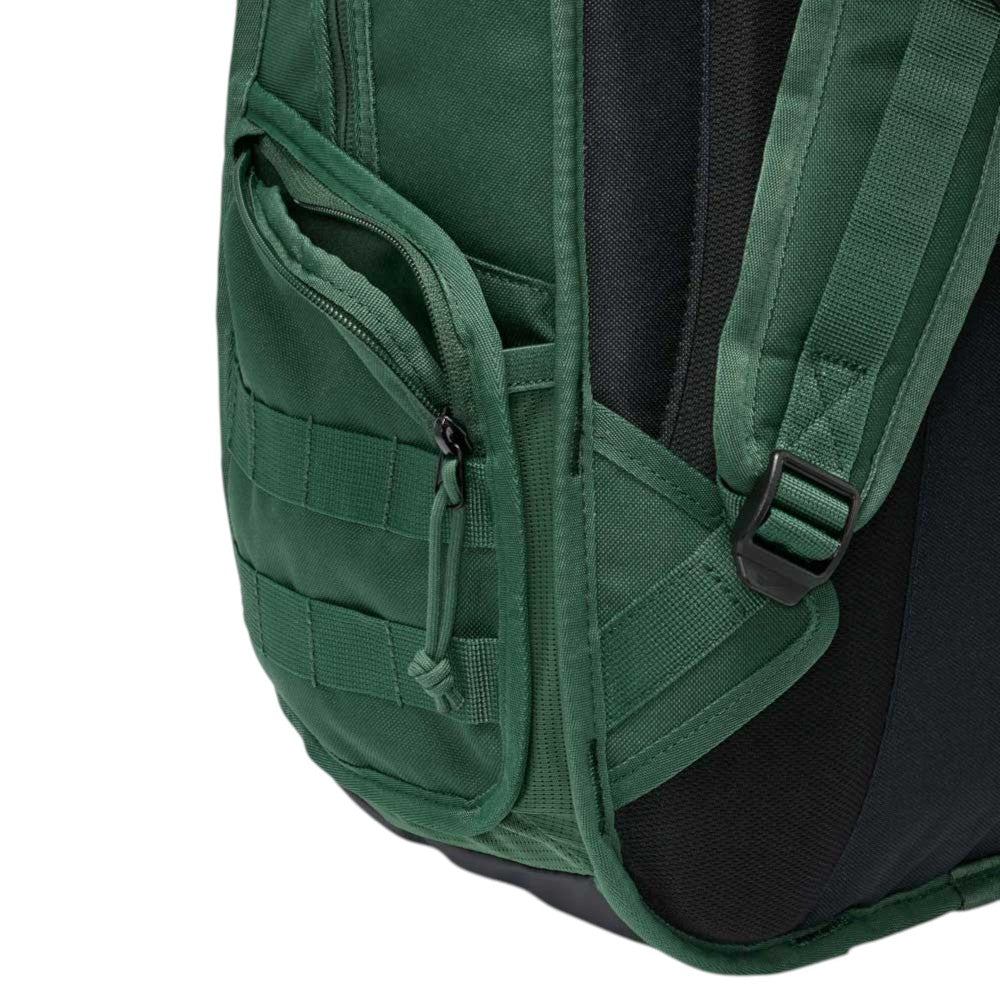 Close-up of the side pocket on the Black Fir FD7544323 Nike SB RPM Skate Backpack, featuring a zipper, black mesh padding, and part of an adjustable shoulder strap with a plastic buckle, shown against a plain background.