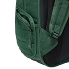 Close-up of the side pocket on the Black Fir FD7544323 Nike SB RPM Skate Backpack, featuring a zipper, black mesh padding, and part of an adjustable shoulder strap with a plastic buckle, shown against a plain background.