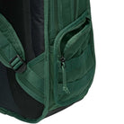 Close-up of the Black Fir FD7544323 Nike SB RPM Skate Backpack in green, highlighting its water-resistant material, partially unzipped front pocket, webbed design, and padded strap against a white background.