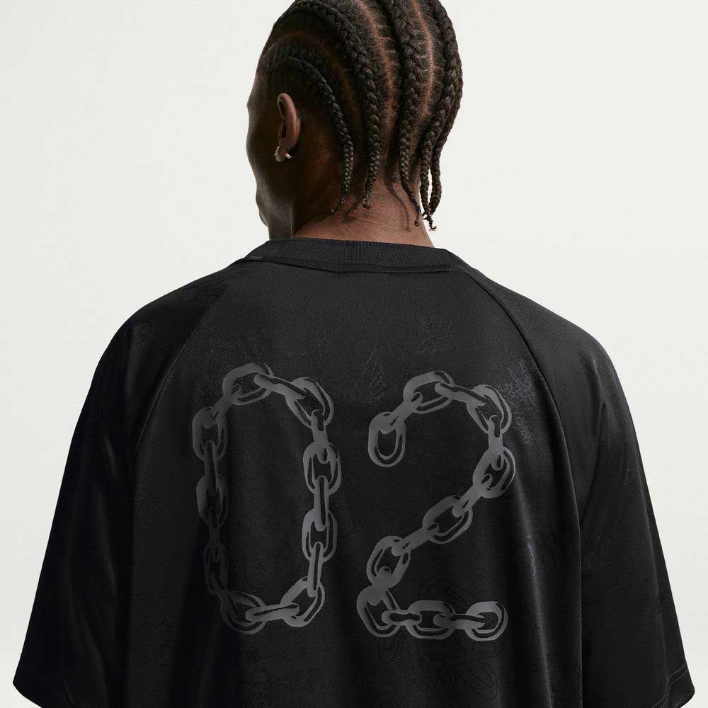 A person with braided hair is seen from the back, wearing a Black Jersey Tee IF1302010 Nike SB Skateboarding T-Shirt against a plain light background. The shirt features sweat-wicking fabric and chain link–styled number 02.