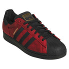 A pair of Black Red Fog KJ5118 Superstar Adidas Skateboarding Suede Shoes featuring a red and black colorway, black laces, a black sole, gold “SUPERSTAR” text on the side, and the iconic three black stripes—designed for classic skateboarding style.
