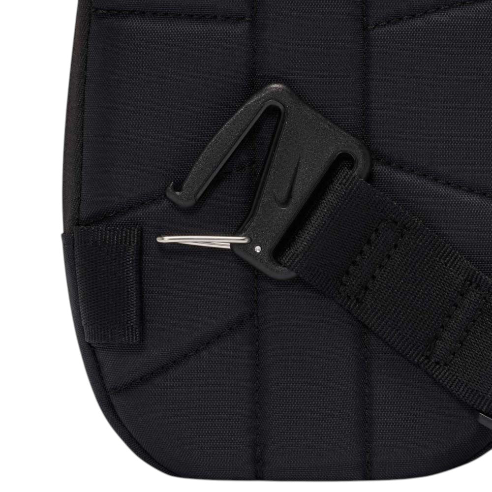 Close-up of a Black Reflect Silver IQ1279010 Nike SB RPM Skate Backpack, showcasing its black fabric construction with a thick strap and a black plastic buckle featuring a hook. The backpack displays visible stitching and includes a small pocket on the left side.