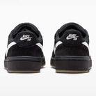 Two Black Summit White Code 58 IB0108001 Nike SB Skateboarding Suede Shoes are shown from the back, featuring white Nike swoosh logos and "Nike" lettering on the heels. The shoes have black midsoles and outsoles accented with a gum-colored edge.