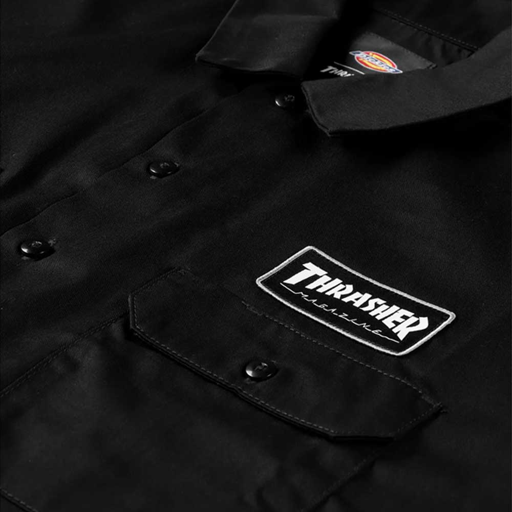 Close-up of the Black Work Shirt Thrasher Magazine x Dickies Skateboarding A88HT BLK, a relaxed fit short sleeve shirt with a “Thrasher” patch above the chest pocket and a Dickies logo on the collar.