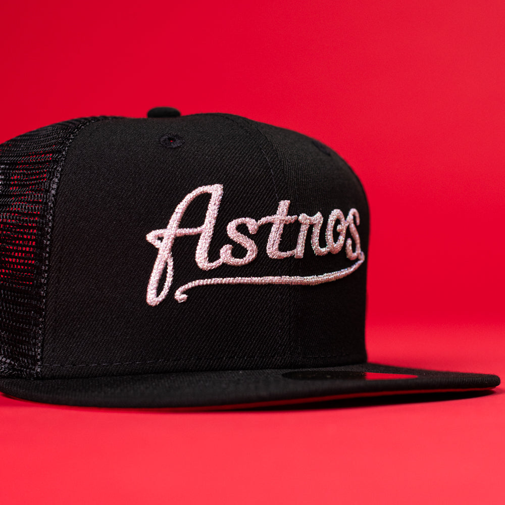 The Black Scarlet Trucker Houston Cougars New Era Hat 5950 Fitted features black mesh and script embroidery, perfect for fans seeking classic style with a fitted trucker look. Displayed on a bold red background.