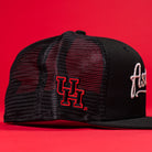 The Black Scarlet Trucker Houston Cougars New Era Hat 5950 Fitted features a black mesh design, red UH embroidery on the side, and white script on the front—perfect for any Houston Cougars fan.