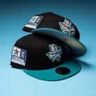 Two Silver Lining Black Teal 2000 Houston Astros New Era Hat 5950 Fitted caps, each featuring a star and Texas logo on the side and a 2000 patch, are displayed on a blue background.