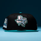 The Silver Lining Black Teal 2000 Houston Astros New Era Hat 5950 Fitted features a black crown with a teal brim, an embroidered Texas outline and star on the front in Chrome Black style, a “2000” patch on the left side, and an extra Houston Astros-inspired star detail.