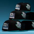 Four Silver Lining Black Teal 2000 Houston Astros New Era Hat 5950 Fitted caps are stacked, each showcasing a chrome black Texas state outline, a star, and a 2000 patch on the side—paying tribute to the Houston Astros. The background features a blue gradient.