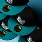 Five black and teal Silver Lining 2000 Houston Astros New Era 59FIFTY fitted hats are arranged in a diagonal pattern on a blue background. Each hat features gold sizing stickers on the brim and bold Chrome Black accents, highlighting the standout design of these Silver Lining Black Teal Houston Astros caps.