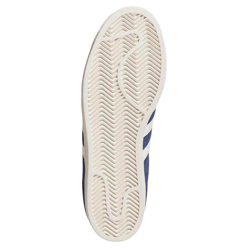The image displays the bottom sole of the Blue White KJ5113 Superstar Adidas Skateboarding Suede Shoes, featuring a classic zigzag herringbone tread pattern. The mostly white sole includes subtle textured details, while a hint of blue edging on the left side reflects the timeless design associated with Adidas’ Superstar ADV skateboarding footwear.