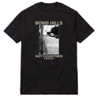 The Bomb Hills Not Countries Black GX1000 Tee Gray Font showcases a striking black-and-white photo of a street hill with a prominent STOP road marking. The gray font above the image reads “BOMB HILLS,” while the text below states “NOT COUNTRIES,” making this tee a standout addition to any collection.