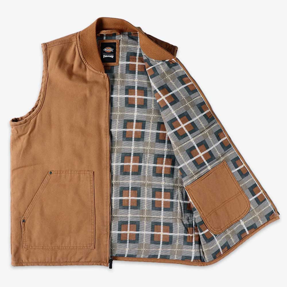 The Brown Duck Vest Thrasher Magazine x Dickies Skateboarding A88IT 0BD is a brown sleeveless zip vest with a gray, white, and brown plaid lining, an interior right pocket, and a relaxed fit inspired by the Dickies x Thrasher collection.