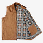The Brown Duck Vest Thrasher Magazine x Dickies Skateboarding A88IT 0BD is a brown sleeveless zip vest with a gray, white, and brown plaid lining, an interior right pocket, and a relaxed fit inspired by the Dickies x Thrasher collection.