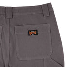 Close-up of the back pocket of Built to Grind Utility Shorts Pewter Bottom Mens Independent, showing a black and orange patch that says “Built to Grind Independent.” These shorts feature belt loops, reinforced stitching, and rugged style.
