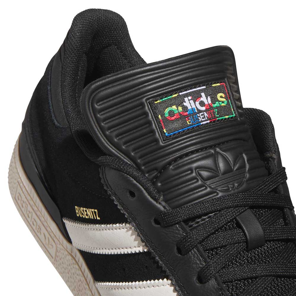 Close-up of Busenitz Black White HQ4708 Adidas Skateboarding Suede Shoes: black with white stripes, gold Busenitz text, textured tongue, and vibrant Adidas logo patch. Durable skate shoes designed for style and performance.