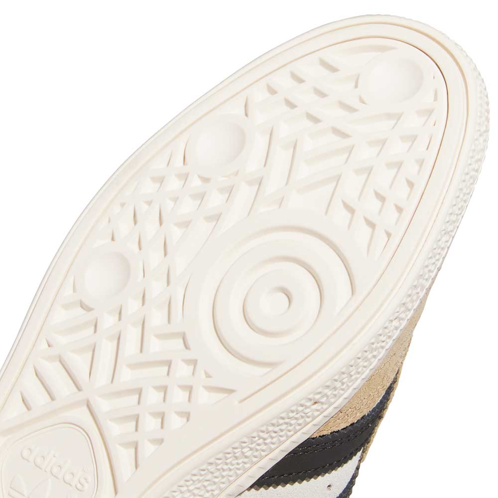 Close-up of the sole on Busenitz Tan White Black HQ4746 Adidas Skateboarding Suede Shoes, showing a white textured rubber bottom. The upper in durable suede with black stripes is also visible.