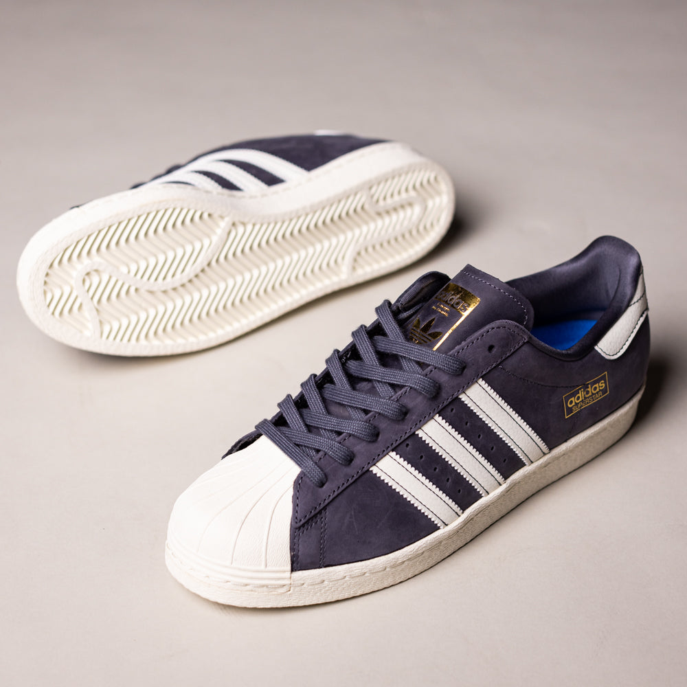 A pair of grey and white adidas Superstar 80 ADV HQ9289 Leather Skateboarding Shoes—one upright, one on its side—displays the durable sole, signature stripes, and classic white toe caps.