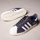 A pair of grey and white adidas Superstar 80 ADV HQ9289 Leather Skateboarding Shoes—one upright, one on its side—displays the durable sole, signature stripes, and classic white toe caps.