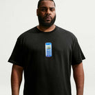 A man wearing the Nike SB Cell Phone Tee Black IM4424010 T-Shirt, featuring a blue retro cell phone graphic on the chest, stands against a plain white background, highlighting its sweat-wicking comfort and casual skateboarding style.