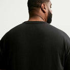 A man with short hair and a beard is pictured from behind, wearing the black Nike SB Cell Phone Tee (IM4424010), a skateboarding T-shirt, against a light background.