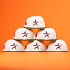 Six Stars Over Houston UH New Era Hat 5950 Fitted caps in white, each with the Houston Cougars star logo, are stacked pyramid-style against a bright orange background.