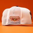 White mesh baseball cap with an embroidered Truckee National Championship 2021 Las Vegas patch on the side, set against an orange background—The Wrangler Chrome Rust Sugarland Space Cowboys New Era Hat 5950 Fitted brings standout style to your collection.
