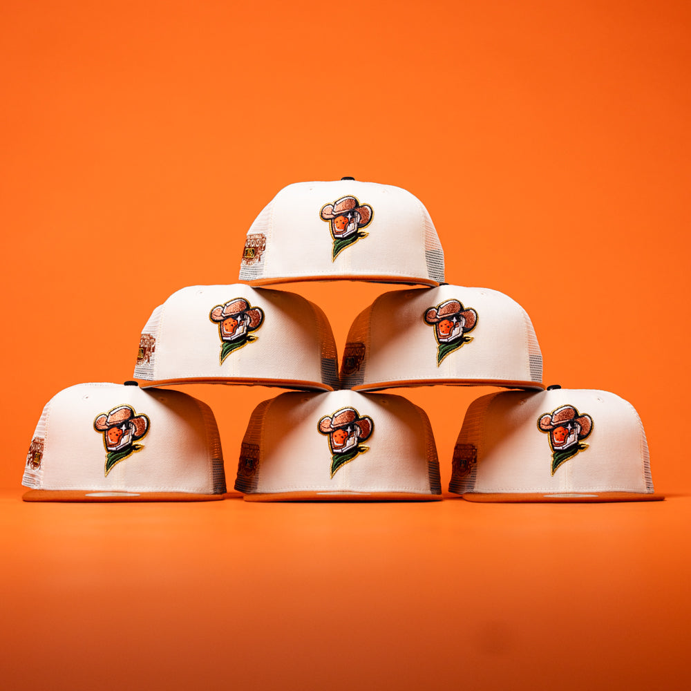 Six The Wrangler Chrome Rust Sugarland Space Cowboys New Era Hat 5950 Fitted caps are stacked in a pyramid shape against an orange background, reminiscent of the playful style found in classic New Era collections.