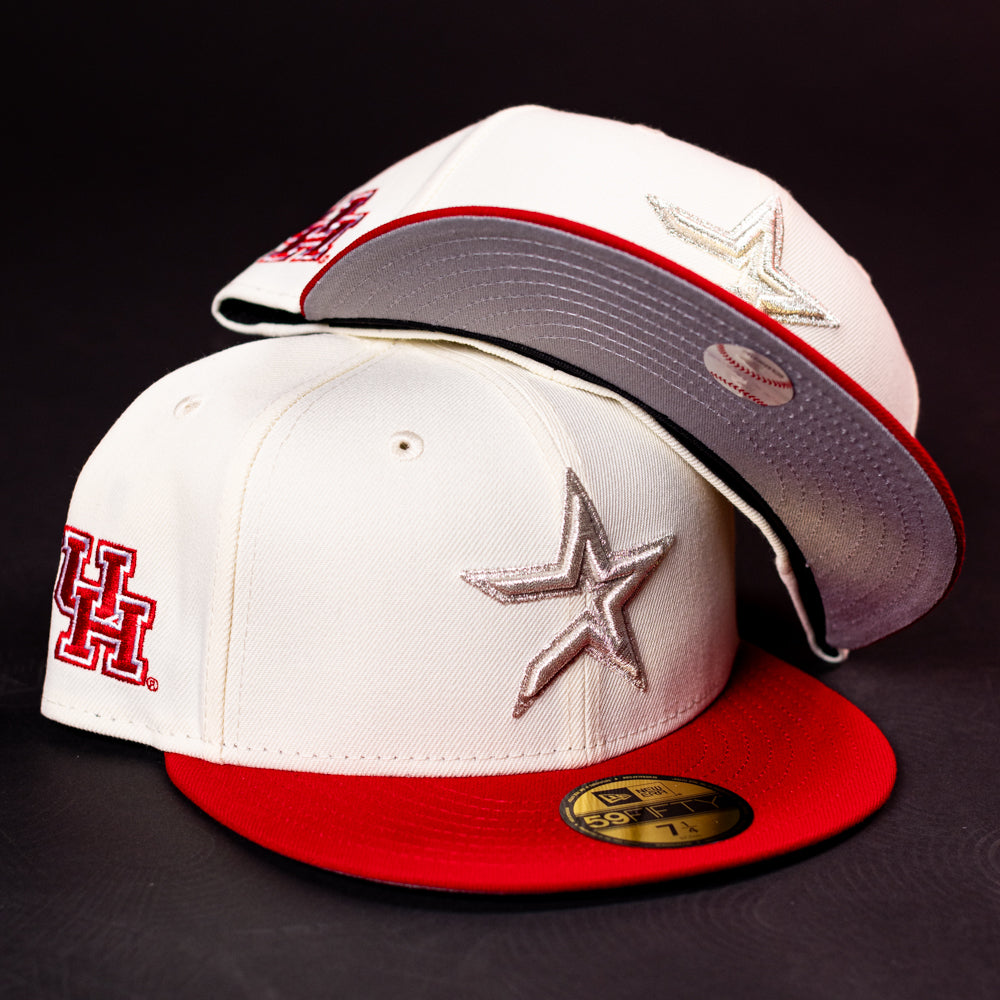 Two cream-colored The Carter Chrome Scarlet Houston Cougars New Era 5950 Fitted baseball caps with red brims. One showcases a bold red UH logo in tribute to the Houston Cougars, while the other features a striking silver star emblem. Both hats retain their original stickers and are set against a sleek black background.