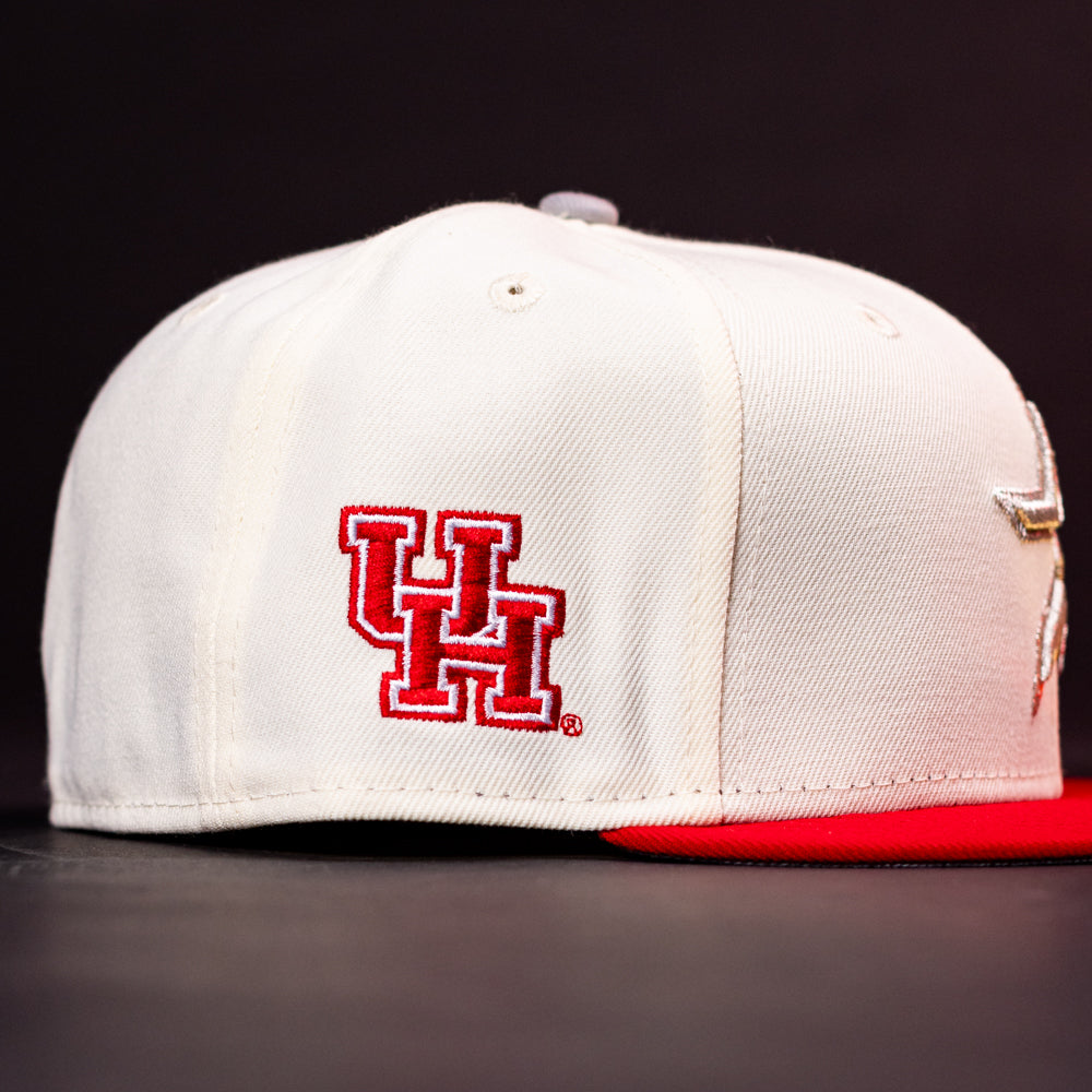 The Carter Chrome Scarlet Houston Cougars New Era Hat 5950 Fitted is displayed on a dark surface against a black background. This white cap features the bold red and white UH logo on the side, while its partially visible red brim adds a striking accent to the iconic fitted design.
