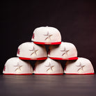 Six The Carter Chrome Scarlet Houston Cougars New Era Hat 5950 Fitted caps—white with red brims and a silver star on the front—are arranged in a pyramid shape against a dark background. These hats deliver bold, contemporary style, making them the perfect standout headwear choice for Houston Cougars fans.