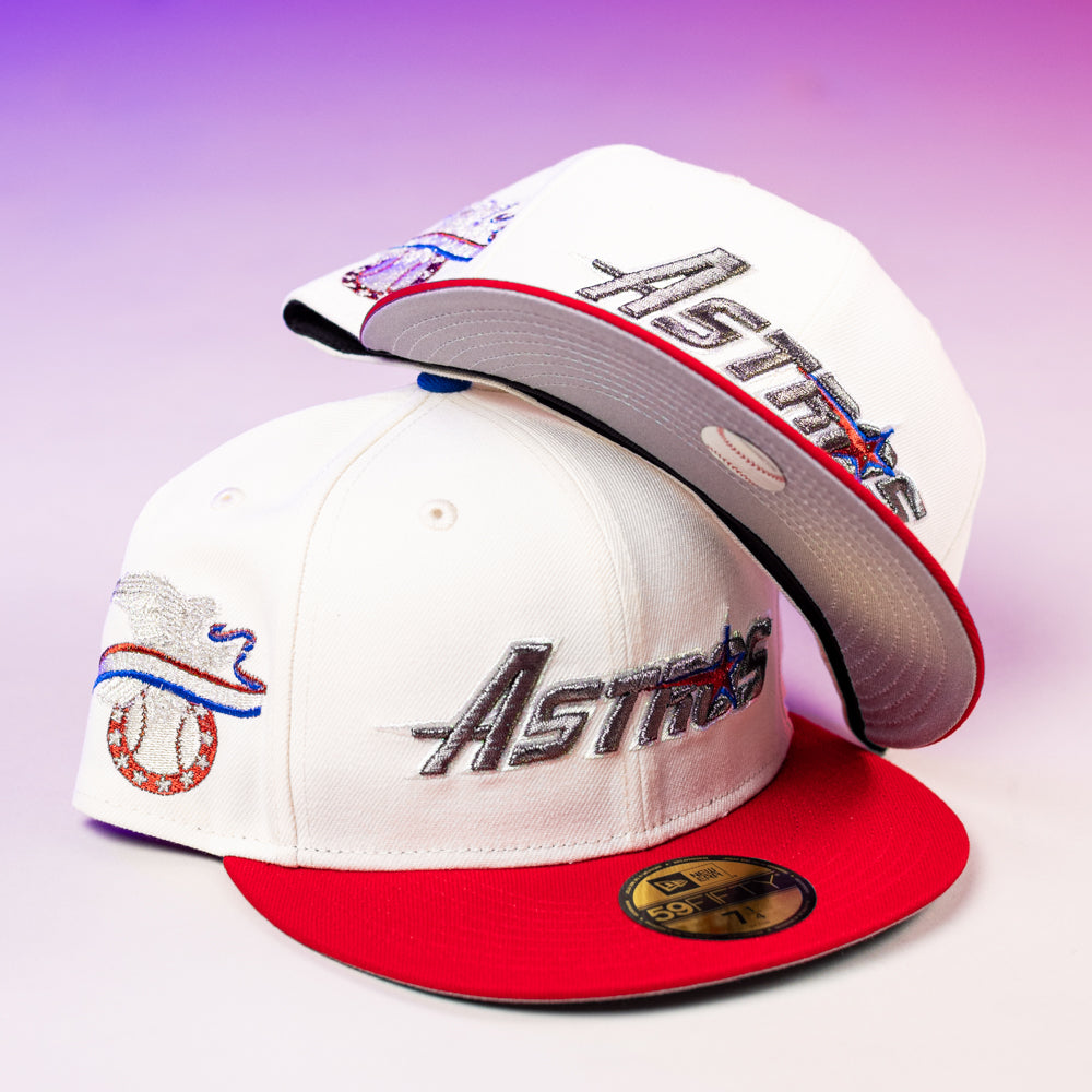 Two The Diplomat Chrome Scarlet Houston Astros New Era 5950 Fitted hats are shown, one flat and one propped up. Both feature embroidered logos on white fabric with red brims, set against a purple and pink gradient background.