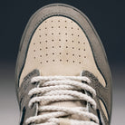 Close-up of the toe area of the 480 CVL New Balance Numeric x Civil Suede Leather Skateboarding Shoe, showcasing its durable beige suede construction with gray accents. The shoe features perforations on the toe box, an ABZORB midsole for added comfort, and white braided laces.