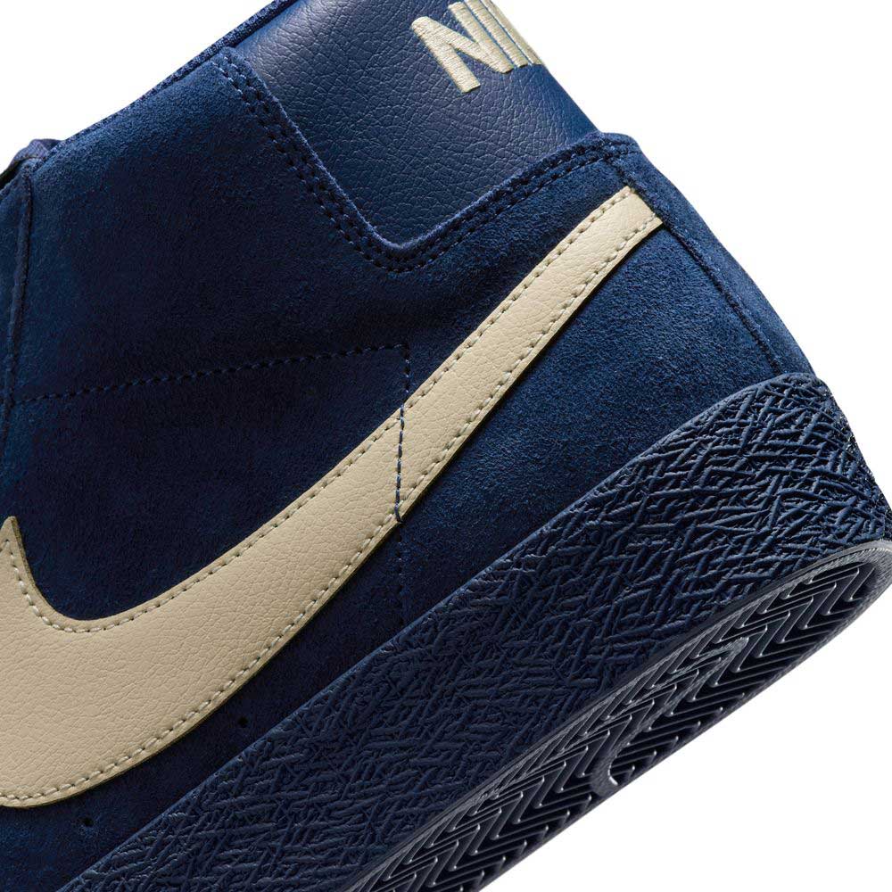 Close-up of the heel and side of the Coastal Blue Pale Yellow IO0667400 Blazer Mid Nike SB Suede Skateboarding Shoe, featuring a beige swoosh logo and textured rubber sole for responsive cushioning and stylish skate performance.
