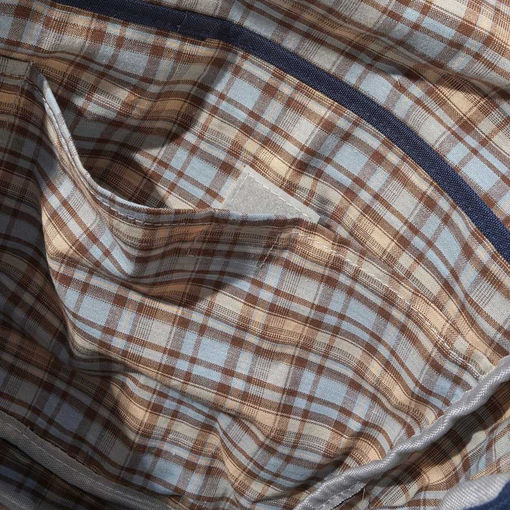 A close-up of the soft, slightly wrinkled fabric with a brown, blue, and white plaid pattern shows the pocket and seams with trim—ideal for the Butter Goods Crossbody Bag Sky Tan, featuring heavy cotton and an adjustable shoulder strap.