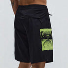 A person wearing the Illusion 21 inch Trunk Black Former, which features a green graphic of audio speakers on the side, standing against a plain light background.