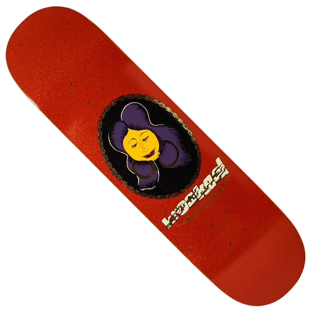 The DBX Chain Manderson 8.38 Krooked Skateboard Deck features a red base, yellow-faced purple-haired woman in a gold oval, and “Krooked” in white near the lower right side.