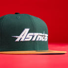 The El Tuga Houston Astros New Era Hat 5950 Fitted is a green cap with "Astros" embroidered in white, a gold star on the front, a gold brim, and a bright red background.
