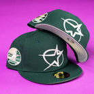 Two Merc Green Silver 35th Houston Astros New Era 5950 Fitted hats with white star logos and multiple patches are displayed on a bright purple background. One is upright, the other tilted to show the underside of the brim.