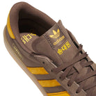 The Daewon Song Glenburn Brown Yellow KZ8777 Adidas Skateboarding Shoes feature a brown design with yellow stripes and logo, with Korean text displayed on the tongue. Captured from an angled overhead perspective, this street style sneaker highlights both its side and top details.