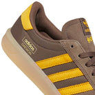 Close-up of the Daewon Song Glenburn Brown Yellow KZ8777 Adidas Skateboarding Shoe, featuring yellow stripes, a yellow heel detail, and “adidas DAEWON” printed on the side. Perfect for fans of street style sneakers, this shoe offers a light rubber sole and brown laces for a classic yet modern look.