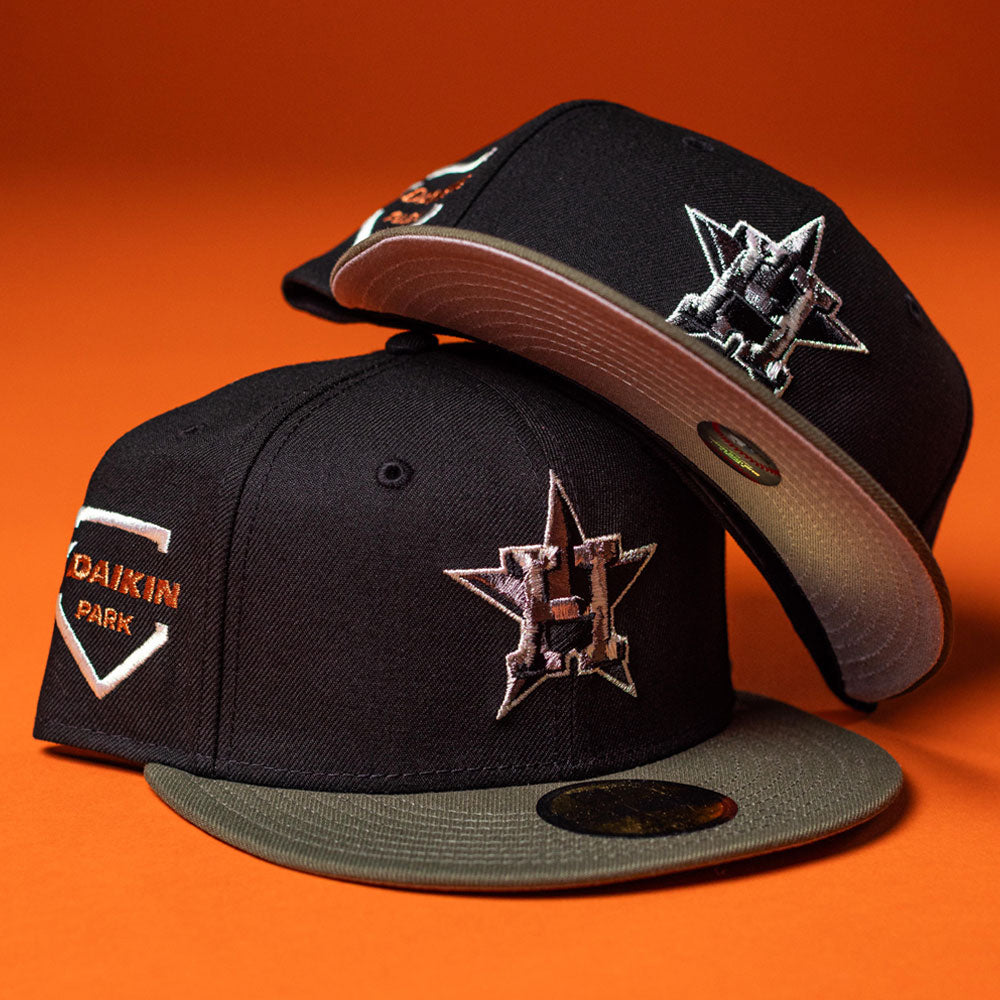 The Daikin Park Olive Houston Astros New Era 5950 Fitted hats feature black crowns, olive brims, a metallic H star logo, and an orange background. One displays a Daikin Park patch on the side.